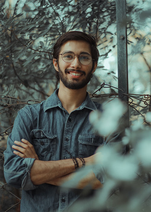 Happy man wearing glasses standing in the trees looking at the camera